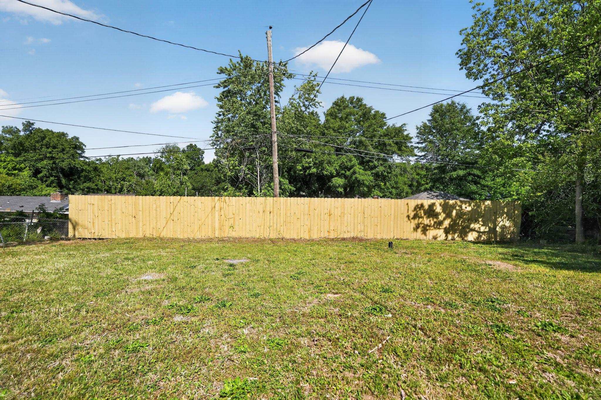 3445 Powers Road Memphis, TN 38128 - Photo 9 of 35 Expansive grassy lot featuring a newly installed privacy fence, mature perimeter trees, and a clear sky overhead