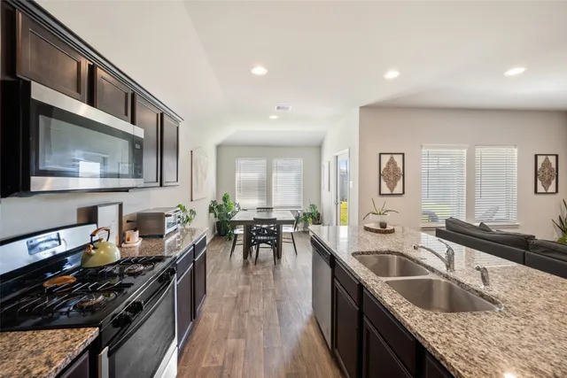 a kitchen with stainless steel appliances granite countertop a table chairs sink refrigerator and cabinets