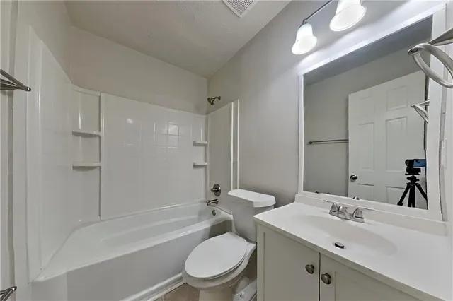 a bathroom with a toilet a sink a mirror a bathtub and vanity