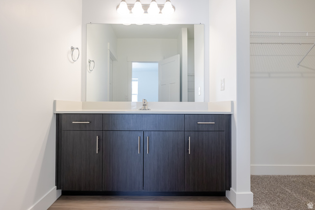 675 West 4500th South, Unit P201 Mapleton, UT 84664 - Photo 9 of 16 Vanity featuring a single undermount sink, a light-toned countertop, and dark wood-finish cabinetry with brushed nickel hardware