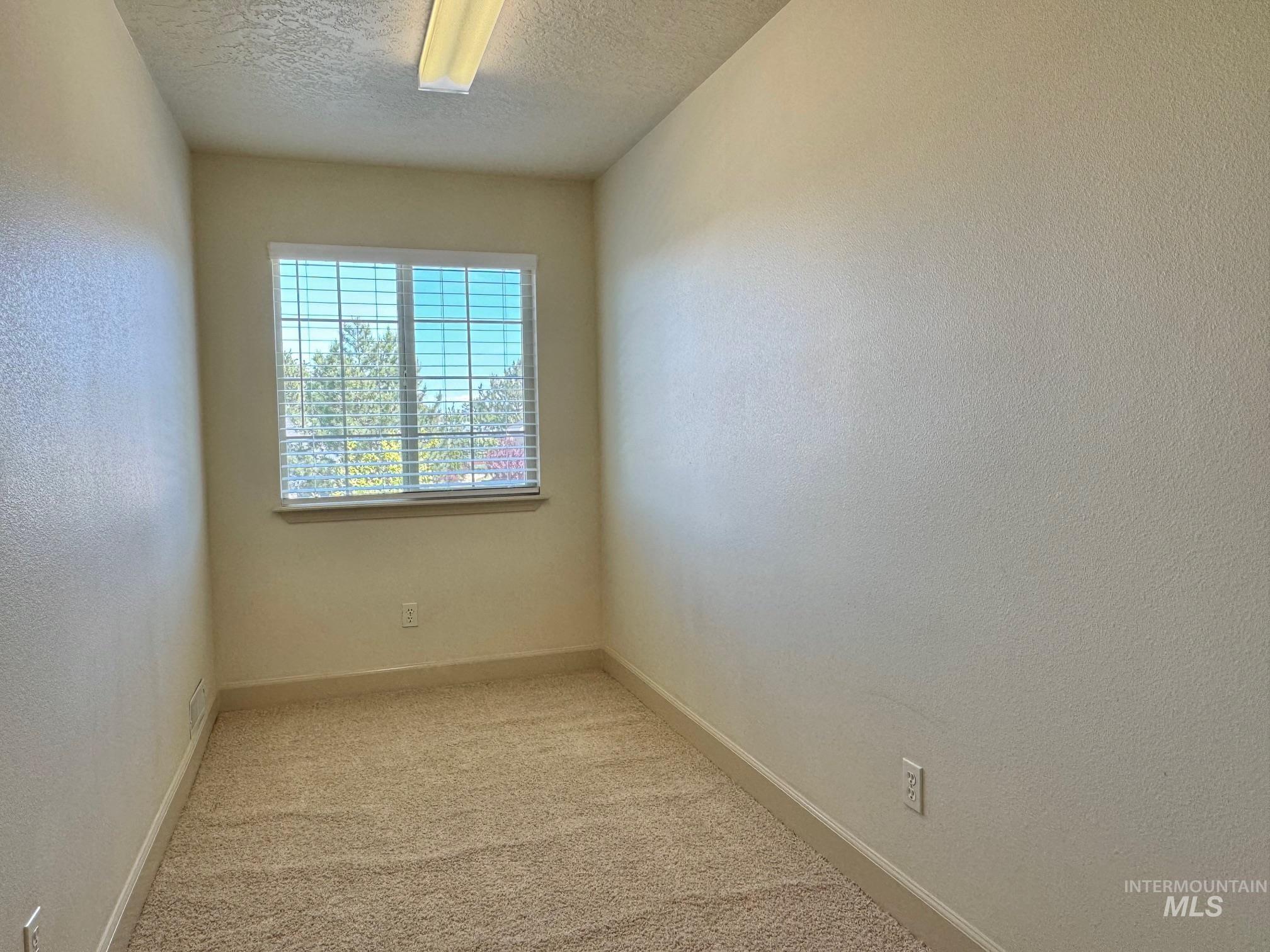 9299 Kemp Road Middleton, ID 83644 - Photo 36 of 50 Compact room with neutral-toned textured walls, a single window with horizontal blinds, and a fluorescent ceiling light fixture