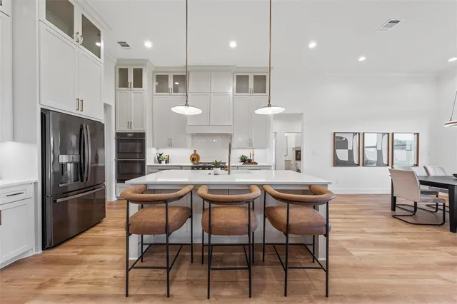 a kitchen with stainless steel appliances kitchen island granite countertop a dining table chairs refrigerator and sink