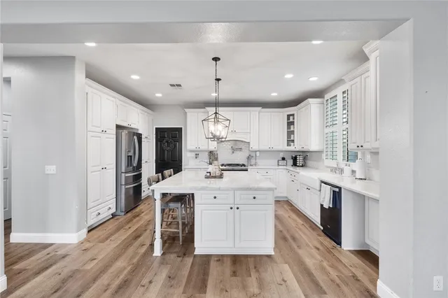 a kitchen with a sink a center island stainless steel appliances and cabinets