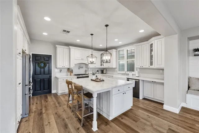 a kitchen with a dining table chairs stove and white cabinets