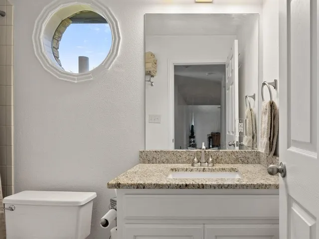 a bathroom with a granite countertop toilet sink and mirror