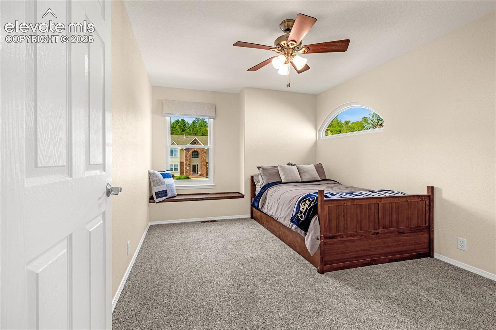 7985 Orchard Path Road Colorado Springs, CO 80919 - Photo 35 of 50 Carpeted room featuring a ceiling fan with integrated lighting, a window seat, a rectangular window with white trim, and an arched transom window