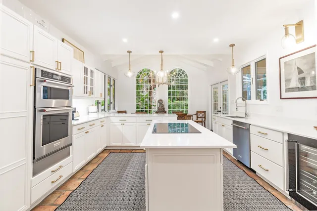 a kitchen that has a lot of white cabinets and stainless steel appliances