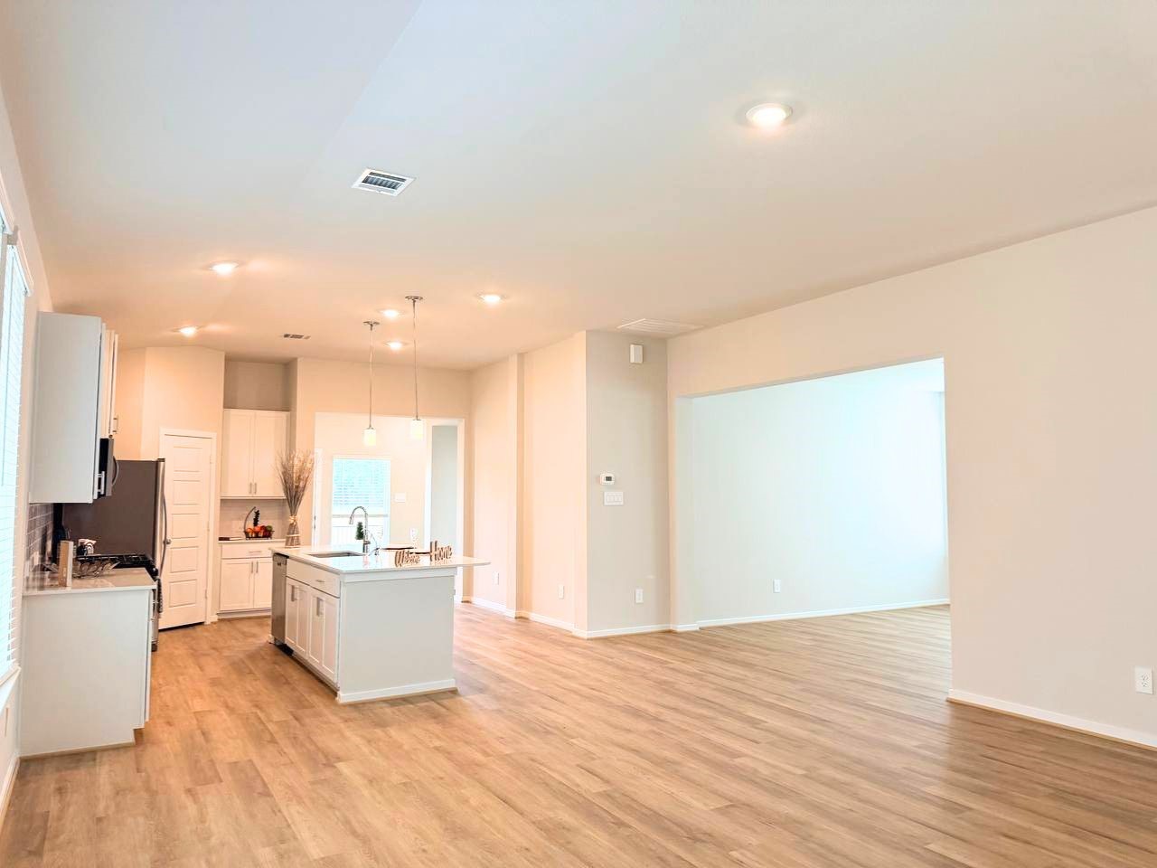 16246 Parish Pointe Court Conroe, TX 77302 - Photo 10 of 32 a view of a kitchen with kitchen island a sink wooden floor and a living room view