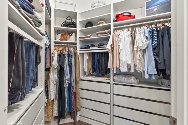 a view of walk in closet with clothes and shoes
