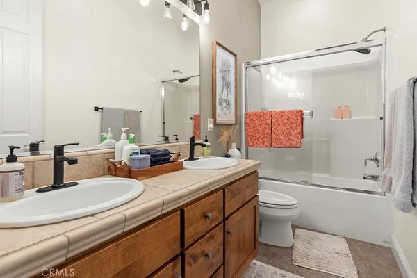 a bathroom with a double vanity sink toilet mirror and shower
