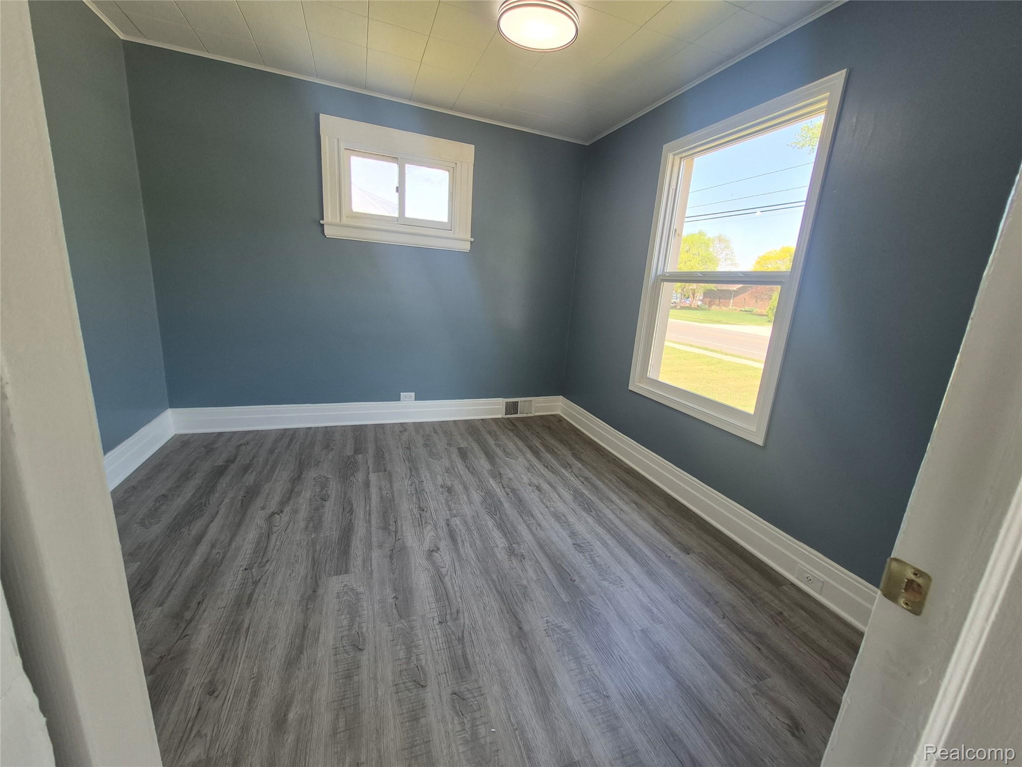16758 Frazho Road Roseville, MI 48066 - Photo 27 of 53 Wood-finish flooring, two windows, blue wall paint, white trim, and a ceiling-mounted light fixture