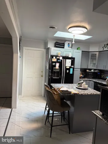 a dining room with stainless steel appliances kitchen island granite countertop a table chairs and a refrigerator