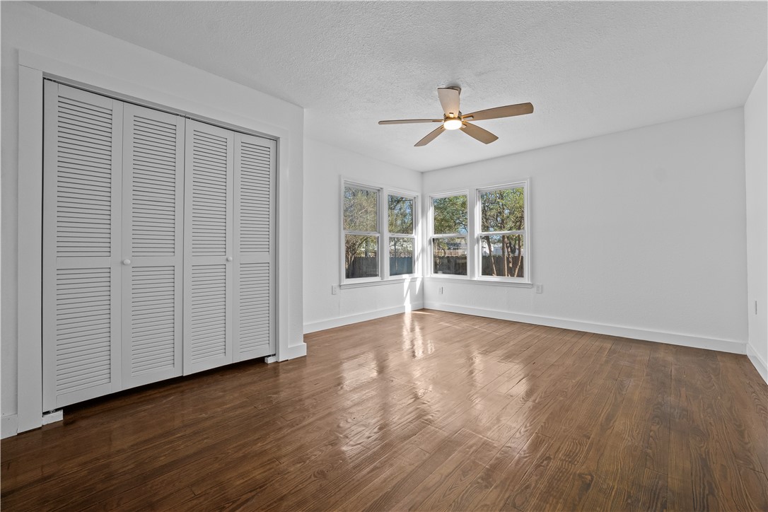 1012 East Main Street Sinton, TX 78387 - Photo 28 of 34 an empty room with wooden floor ceiling fan and windows