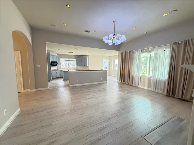 an empty room with wooden floor fireplace and windows