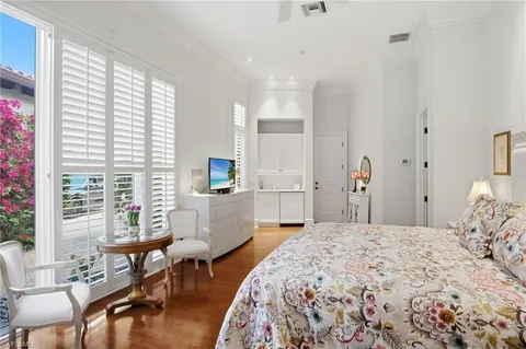 a bedroom with a bed a table and chair with the floor to ceiling window