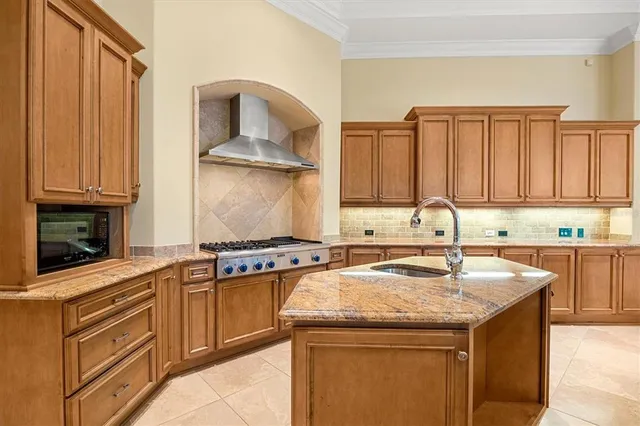 a kitchen with granite countertop a sink a stove and cabinets