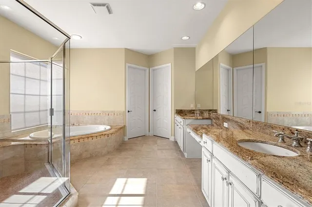 a spacious bathroom with a granite countertop sink a mirror a bathtub and next to a window