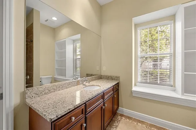 a bathroom with a granite countertop sink and a large mirror