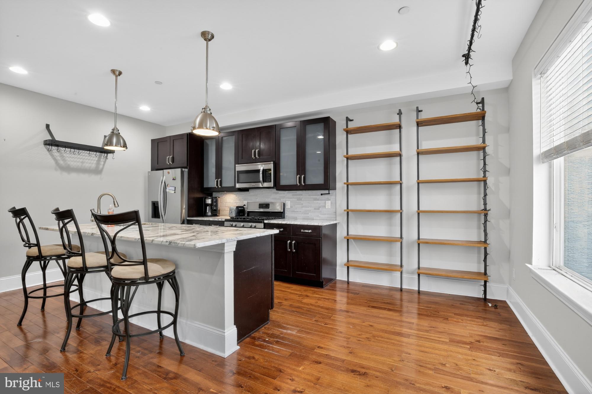 946 North 2nd Street, Unit 5 Philadelphia, PA 19123 - Photo 5 of 31 a kitchen with stainless steel appliances kitchen island granite countertop a stove a refrigerator and a wooden cabinets