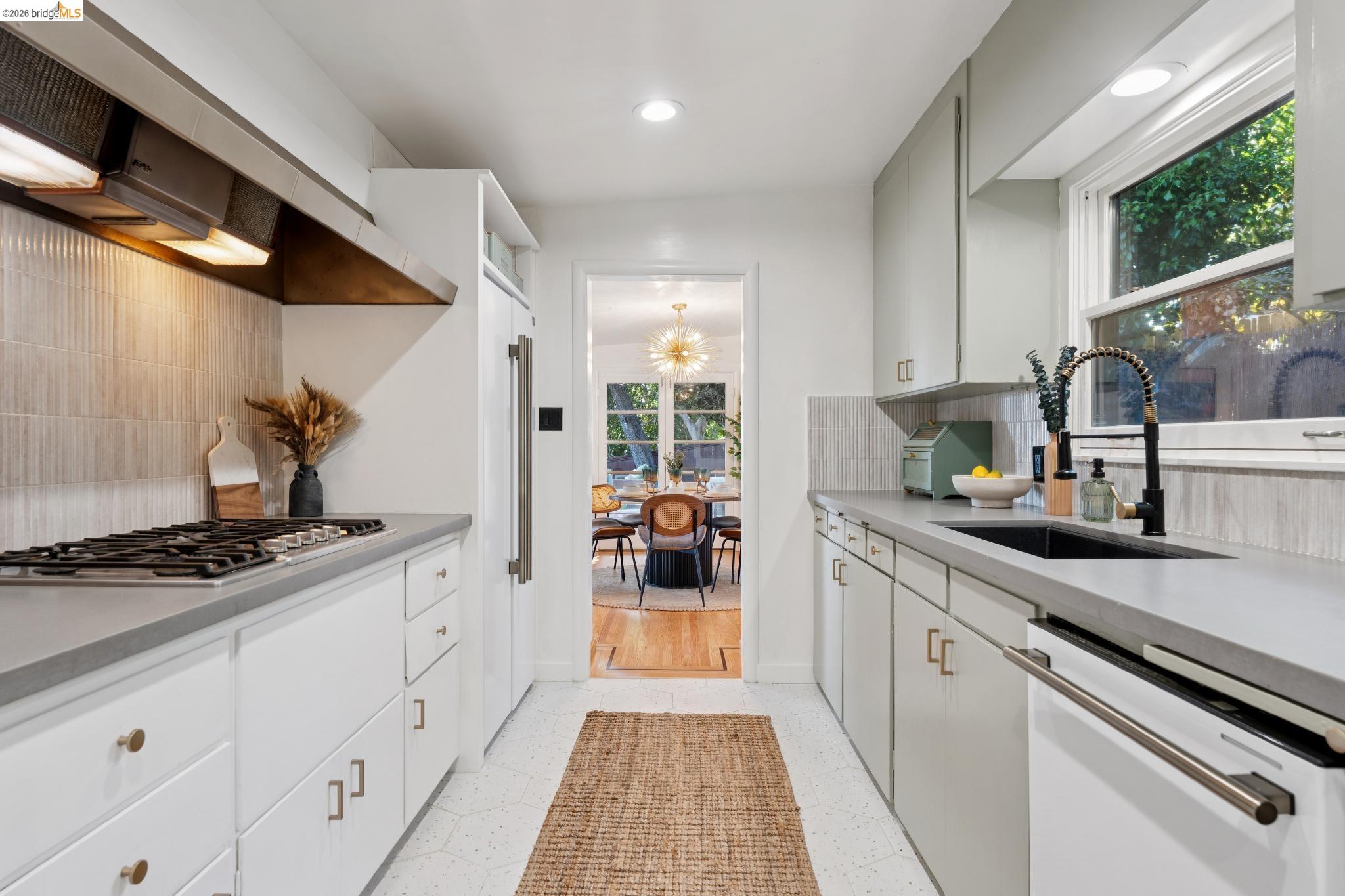 2301 Oak Street Berkeley, CA 94708 - Photo 7 of 61 Galley kitchen featuring white cabinetry, light gray countertops, a gas range, a black sink with a coil faucet, and a large window