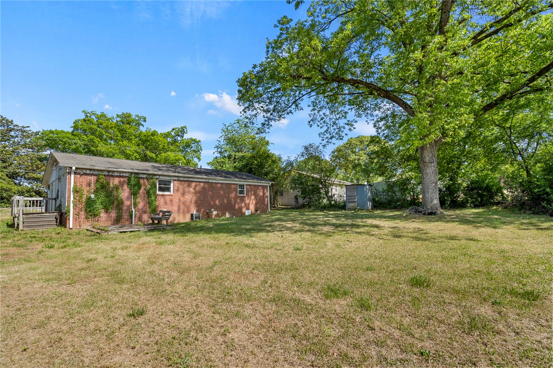 308 Clayton Street Central, SC 29630 - Photo 25 of 31 This spacious backyard offers ample outdoor living potential, featuring a mature tree and a charming brick exterior.