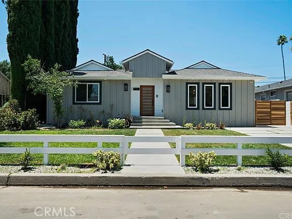 a front view of a house with a yard and potted plants