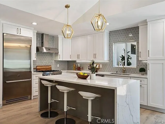 a kitchen with stainless steel appliances granite countertop a sink a stove a refrigerator cabinets and chairs
