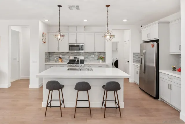 a kitchen with stainless steel appliances kitchen island a table chairs refrigerator and microwave