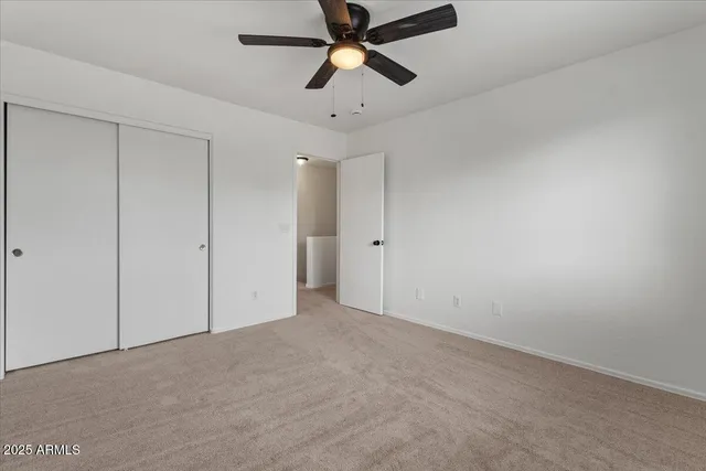 an empty room with windows and a ceiling fan
