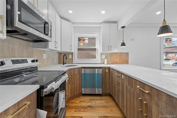 a kitchen with stainless steel appliances granite countertop a sink a stove and a wooden cabinets