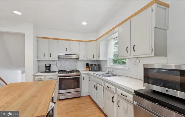 a kitchen with stainless steel appliances white cabinets and a stove top oven