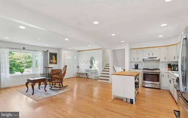 a living room with stainless steel appliances furniture and a kitchen view