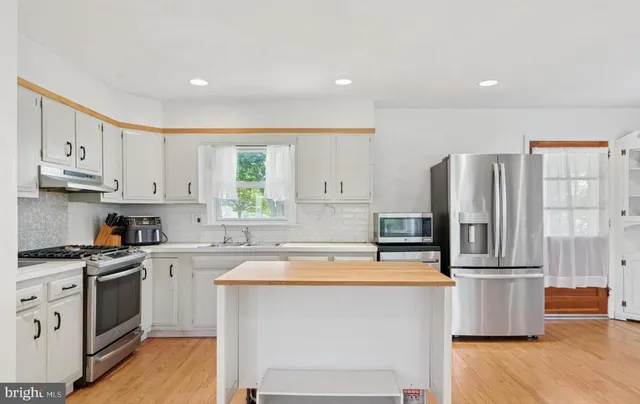 a kitchen with stainless steel appliances granite countertop a refrigerator sink and stove