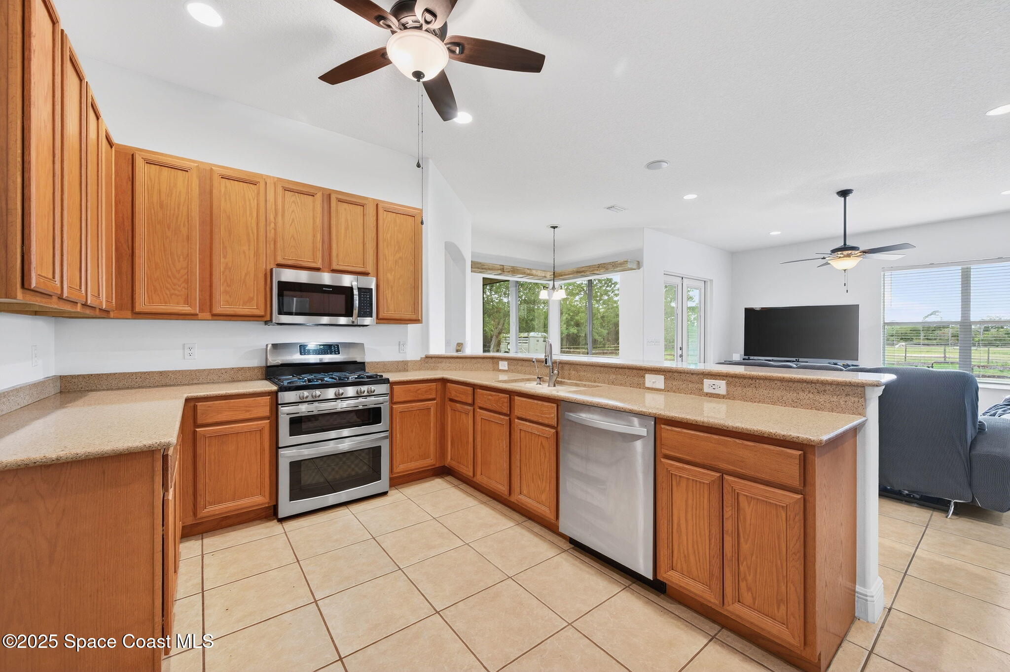 2740 Waring Lane Malabar, FL 32950 - Photo 62 of 98 a kitchen with stainless steel appliances granite countertop a stove top oven a sink dishwasher and a refrigerator with wooden cabinets