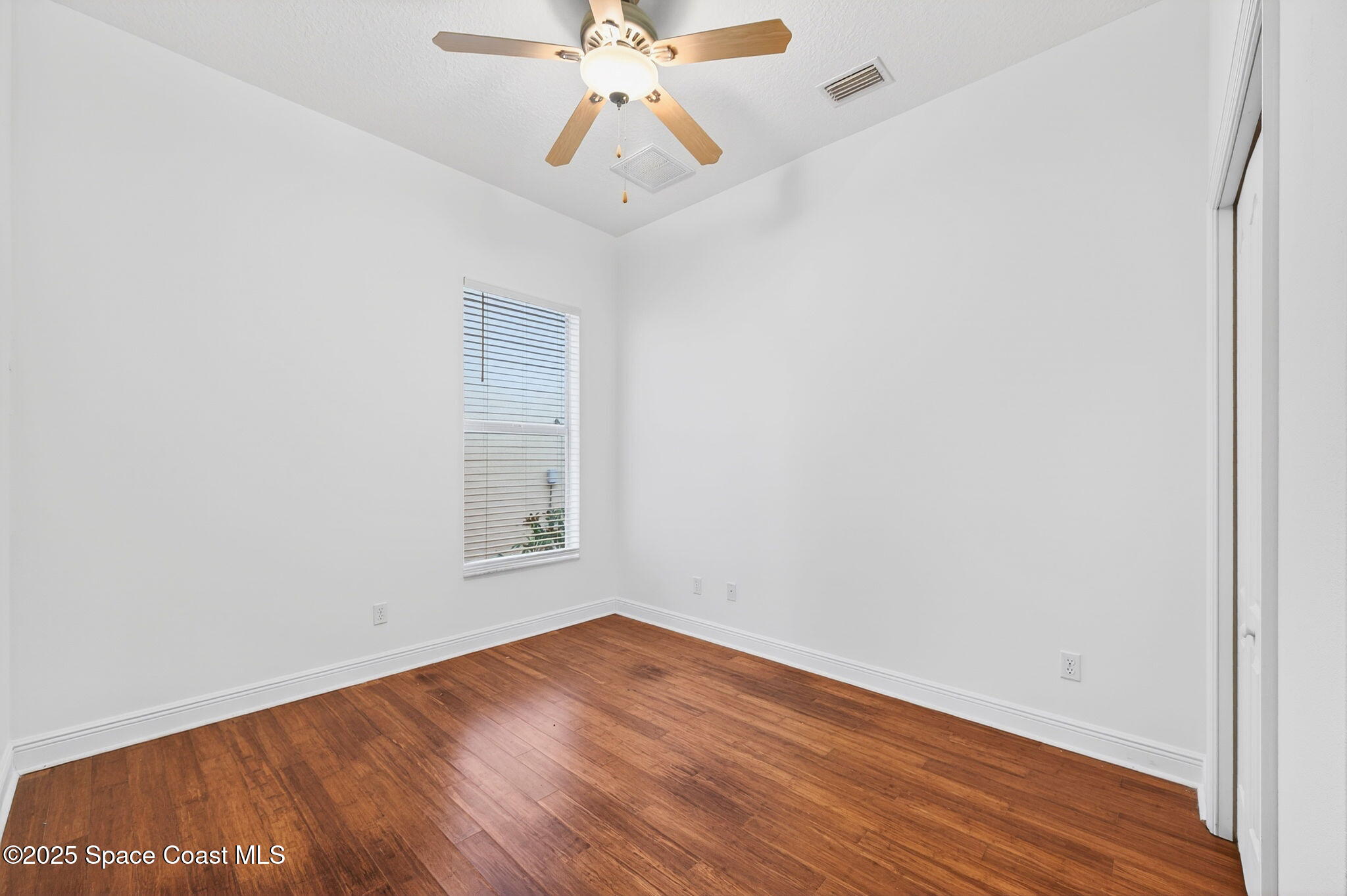 2740 Waring Lane Malabar, FL 32950 - Photo 81 of 98 an empty room with wooden floor chandelier fan and windows