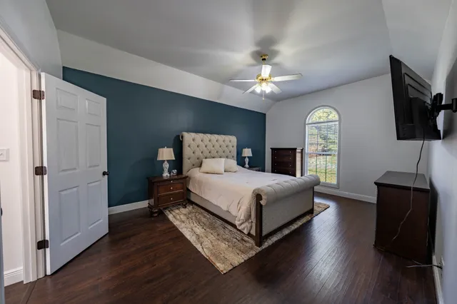 a bedroom with a bed a flat tv screen and dresser