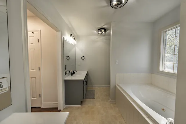 a bathroom with a tub sink and mirror