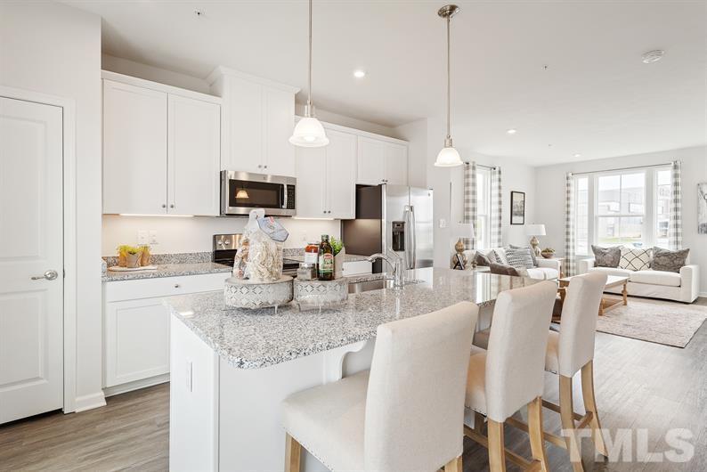 6607 Pathfinder Way Raleigh, NC 27616 - Photo 6 of 6 a large kitchen with kitchen island granite countertop a stove a sink a dining table and chairs with wooden floor