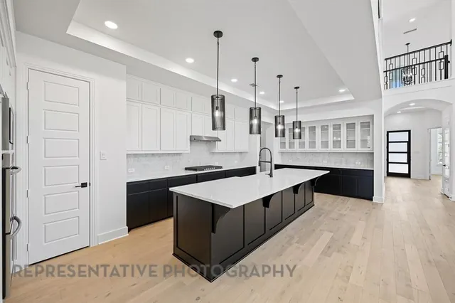 a large white kitchen with kitchen island a sink stainless steel appliances and cabinets