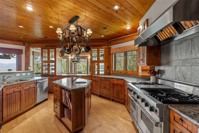 a kitchen with stainless steel appliances granite countertop a sink a stove and a wooden cabinets