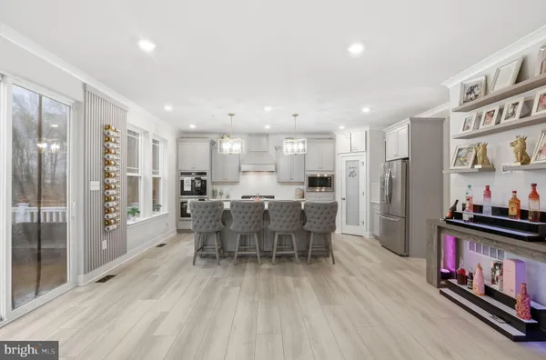 a kitchen with stainless steel appliances granite countertop a dining table chairs refrigerator and microwave