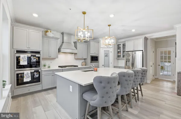 a kitchen with stainless steel appliances kitchen island granite countertop a refrigerator a sink dishwasher a dining table and chairs with wooden floor