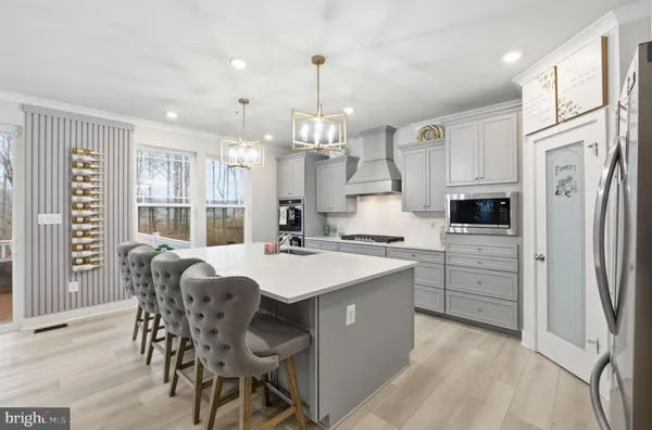 a large white kitchen with a large island oven a sink dishwasher and a fireplace with wooden floor