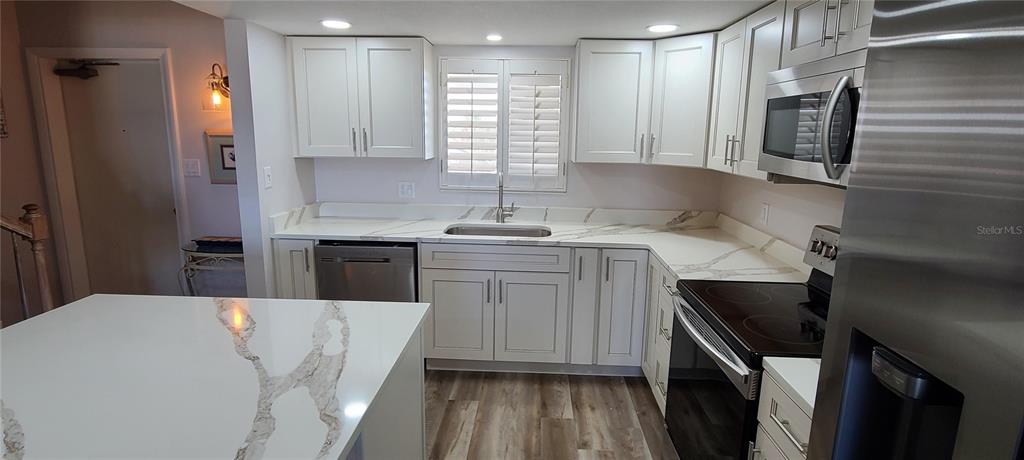 815 Ocean Shore Boulevard, Unit 7B Ormond Beach, FL 32176 - Photo 3 of 19 a kitchen with a sink a microwave a refrigerator and cabinets