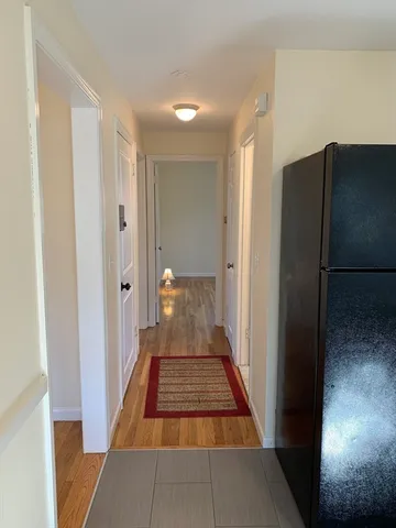 a view of a hallway with wooden floor and a bathroom