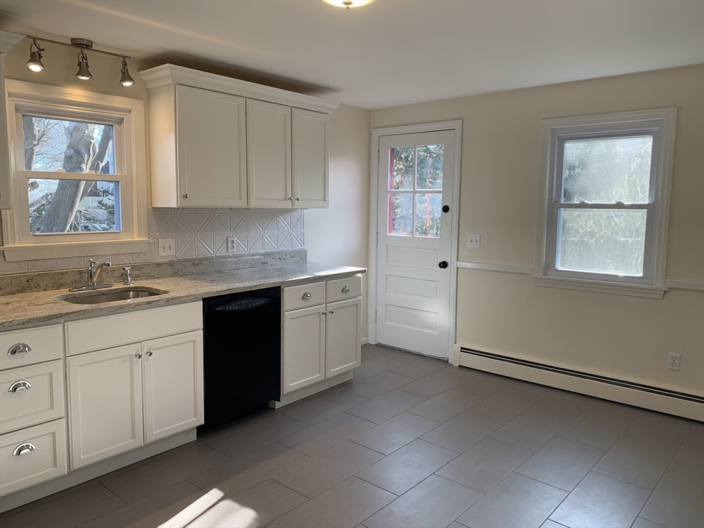 18 Guernsey Street, Unit 2 Marblehead, MA 01945 - Photo 6 of 23 a kitchen with granite countertop white cabinets white appliances with a sink and dishwasher