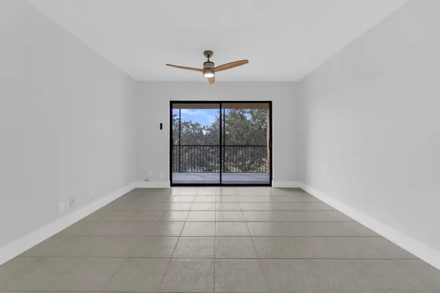an empty room with chandelier fan and windows