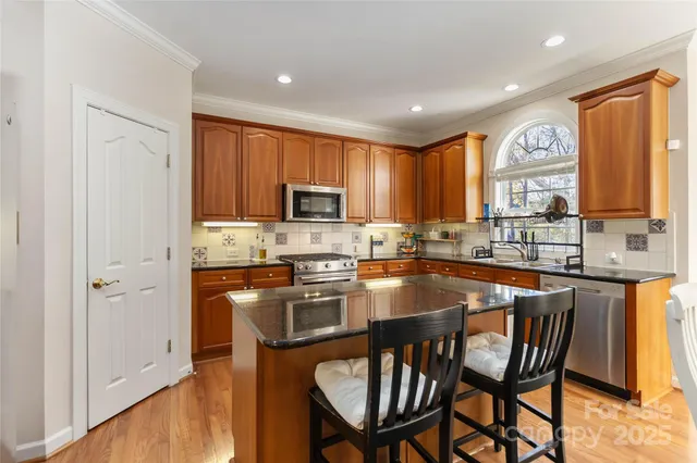 a kitchen with granite countertop a stove top oven a sink a dining table and chairs