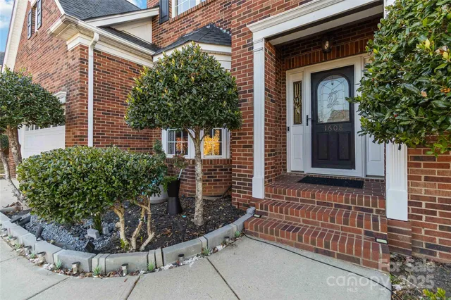 a view of a house with a small yard and potted plants