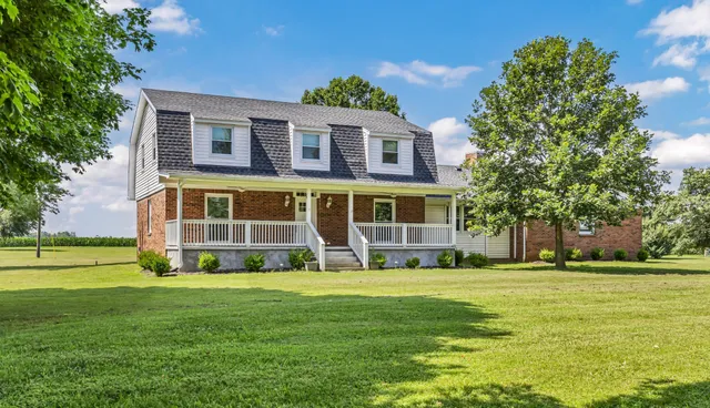 a view of a house with a big yard and large trees
